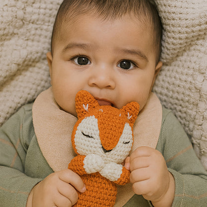 bébé allongé au lit  tient doudou renard marron 