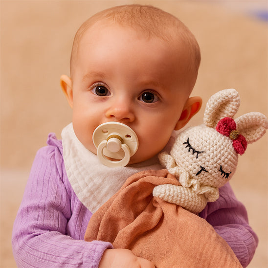 bébé avec suce jaune tient doudou lapin marron