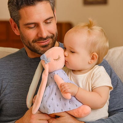 Bébé dans les bras de papa câline peluche lapin longues oreilles