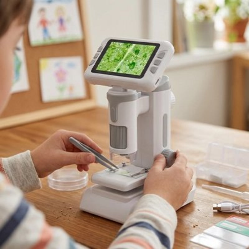 Microscope enfant sur la table et le garçon fait son experience avec la feuille d'arbre