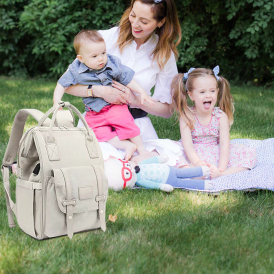 sac-a-langer-bebe-rangement-maman-tient-bébé-bras-soeur-assise-terre-parc